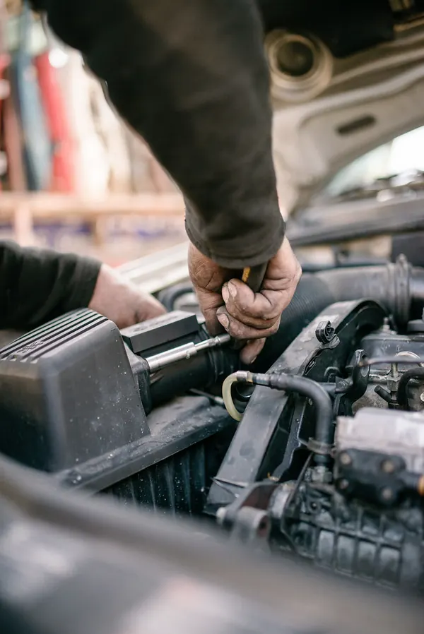 Manos de un mecanico trabajando en el motor de un coche